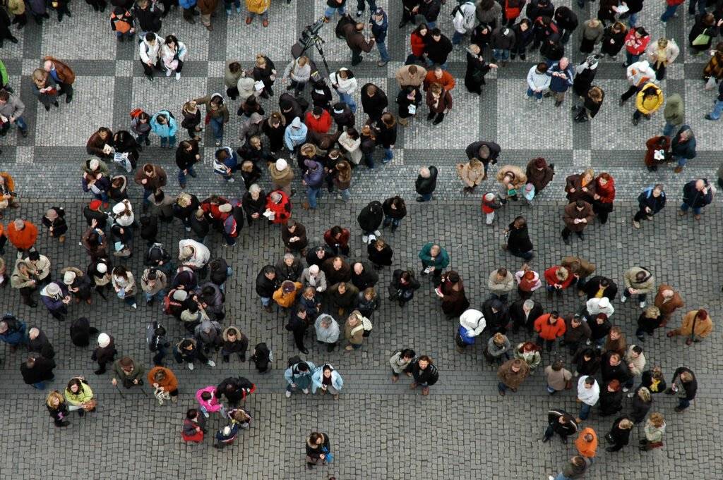 Aerial view of a large crowd of people walking on a paved surface.