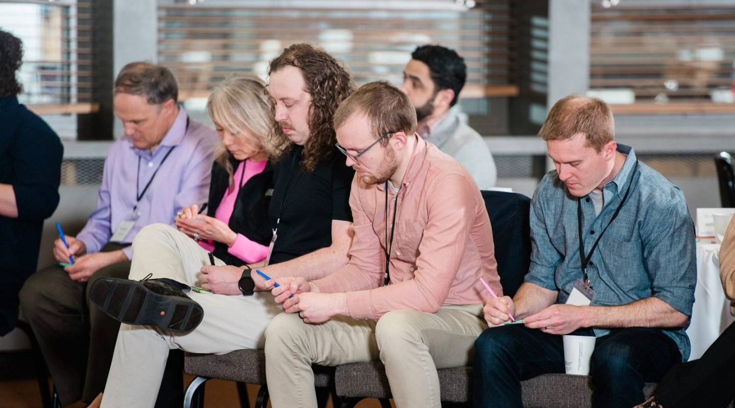 Group of people attending a conference or seminar, sitting and listening attentively.